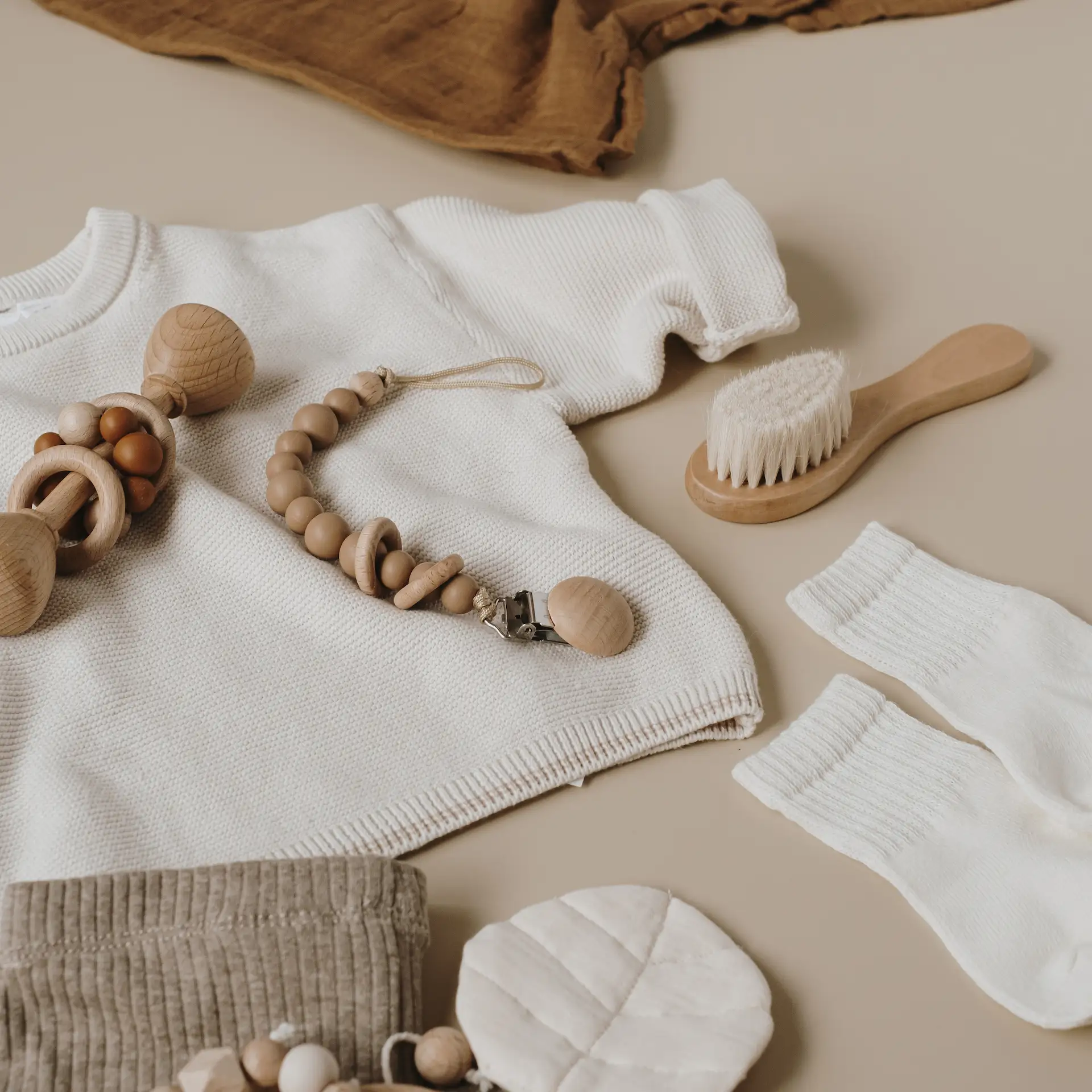 Baby clothes and wooden toys flatlay.